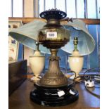 A Victorian double burner oil lamp with glass reservoir, pressed brass pedestal and ceramic base -