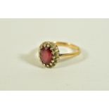 A 9CT GOLD GARNET AND DIAMOND CLUSTER RING, of an oval form, centring on an oval cut garnet,