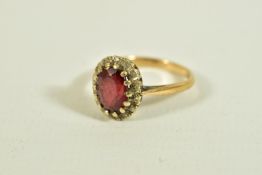 A 9CT GOLD GARNET AND DIAMOND CLUSTER RING, of an oval form, centring on an oval cut garnet,