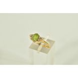 A 9CT GOLD GEM SET DRESS RING, centring on an oval cut green stone assessed as peridot, flanked