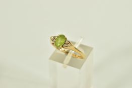 A 9CT GOLD GEM SET DRESS RING, centring on an oval cut green stone assessed as peridot, flanked