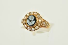 A MEMORIAL RING, the central onyx panel carved to depict a flower within a rope twist surround and