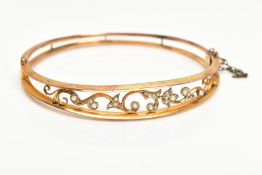 AN EDWARDIAN SEED PEARL BANGLE, hinged openwork floral design set with seed and split pearls, fitted