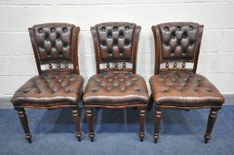 THREE BUTTONED BROWN LEATHER CHAIRS, with a scrolled back, on turned front legs