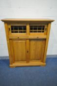 A SOLID GOLDEN OAK DRINKS CABINET, double sliding glazed doors enclosing two compartments with