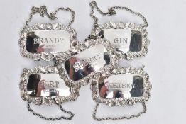 FIVE SILVER DECANTER LABELS, each of a rectangular form with decorative floral and scroll rims,