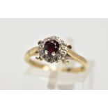 A 9CT GOLD GARNET AND DIAMOND CLUSTER RING, raised cluster centring on a circular cut garnet, within