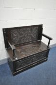 AN EARLY 20TH CENTURY CARVED OAK MONKS BENCH, with foliate decoration and carved mask to the front