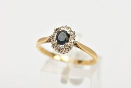 AN 18CT GOLD SAPPHIRE AND DIAMOND CLUSTER RING, centring on a four claw set, oval cut blue sapphire,