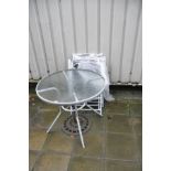 A ROUND GLASS TOPPED GARDEN TABLE 87cm along with four folding chairs