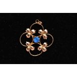 A YELLOW METAL PENDANT, of an openwork foliate design, set with a central circular cut blue paste,