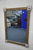 A FRENCH GILTWOOD BEVELLED EDGE WALL MIRROR, with porcelain plaques to each corner, 63cm x 88cm