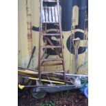 A WHEELBARROW CONTAINING GARDEN TOOLS and a vintage wooden step ladder