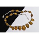 AN IMITATION AMBER NECKLACE, designed as graduated oval cabochons of imitation amber, each in