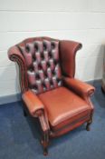 A RED LEATHER BUTTON BACK WINGED ARMCHAIR with cabriole front legs (condition:- some fading to