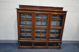 AN EARLY 20th CENTURY TRIPLE DOOR WALNUT GLAZED BOOKCASE with raised back, carved central rail width