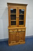 A MODERN PINE BOOKCASE with two glazed doors over two drawers and two cupboard doors width 91cm x