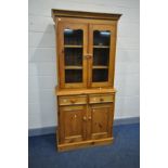 A MODERN PINE BOOKCASE with two glazed doors over two drawers and two cupboard doors width 91cm x