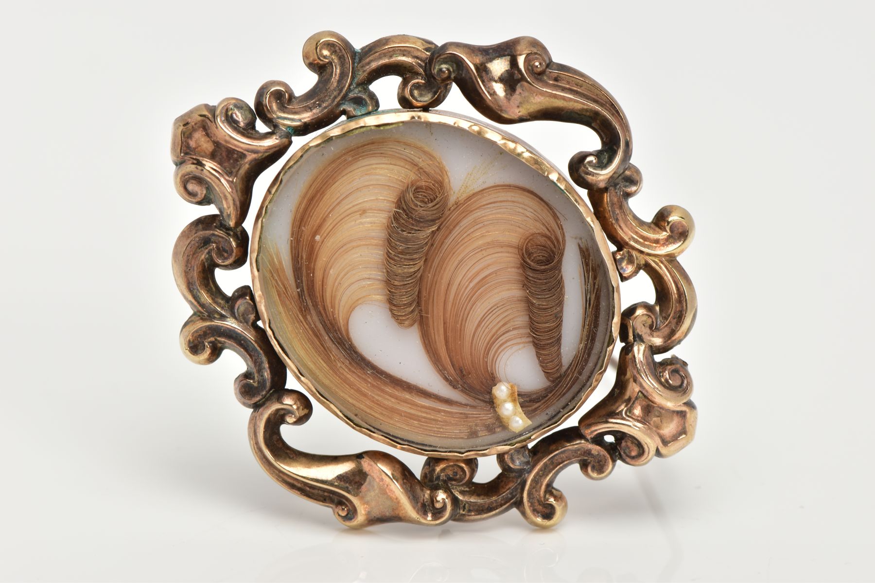 A LATE VICTORIAN MEMORIAL BROOCH, the central oval arranged hair panel with split pearl detail, to