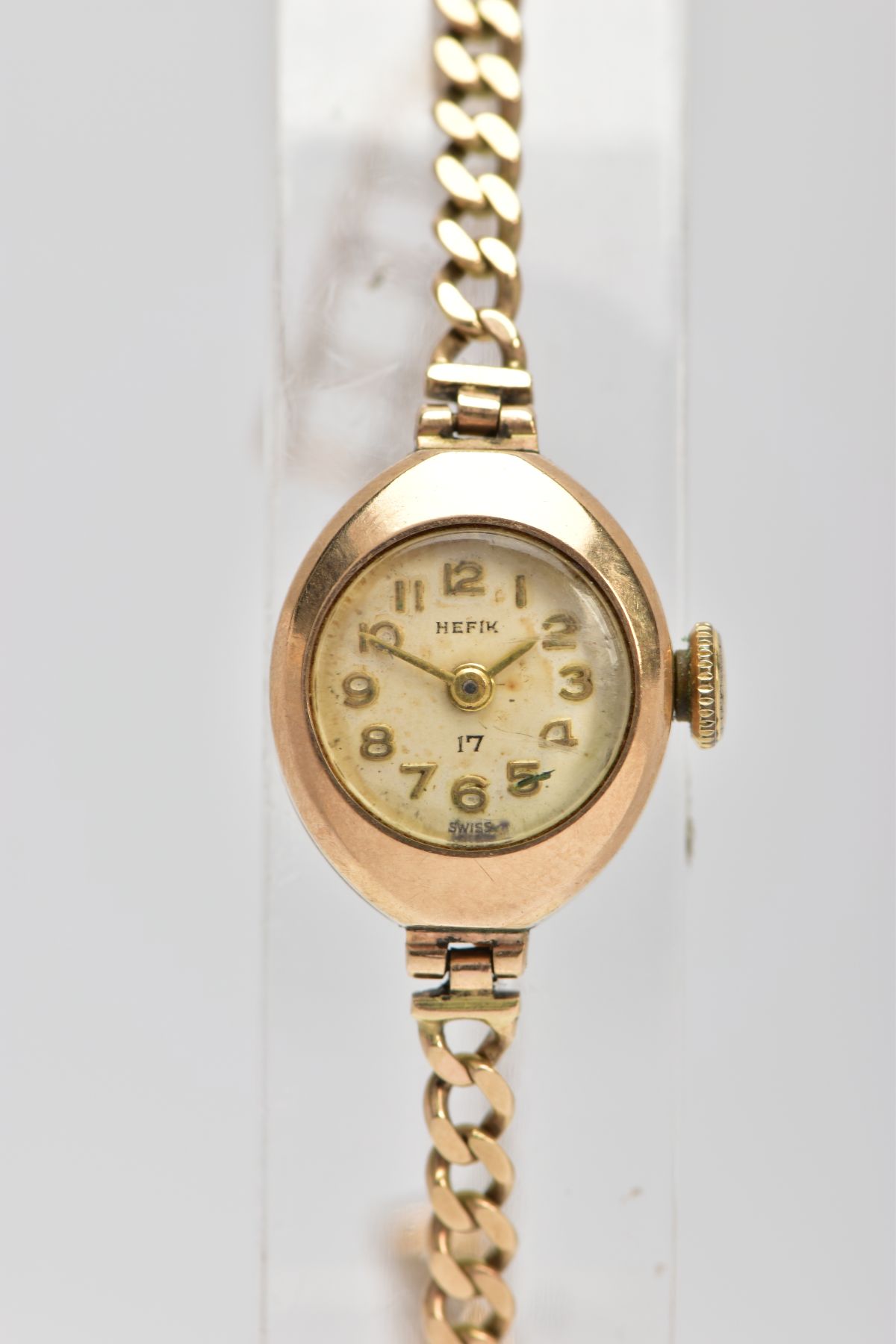 A LADY'S 9CT GOLD WRISTWATCH, a hand wound movement, round discoloured dial signed 'Hefik', Arabic