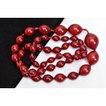 A CHERRY AMBER BAKELITE BEAD NECKLACE, graduated slightly pointed oval beads individually knotted on