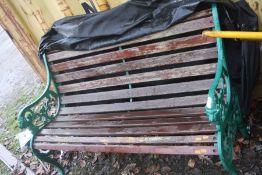 A CAST IRON GARDEN BENCH with slatted hardwood seat and back cm wide along with canvas cover