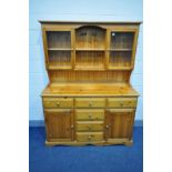 A PINE DRESSER, two central shelves flanked by two glazed cupboard doors, the base with six