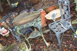 A CAST IRON PUB TABLE with a distressed wooden top 63cm in diameter and two modern garden chairs (