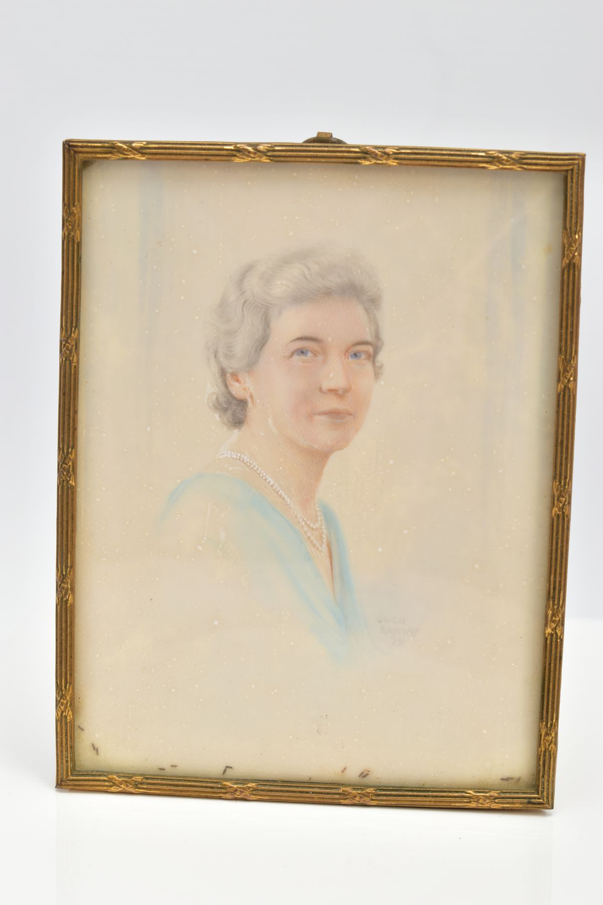 A SMALL PORTRAIT AND BRASS FRAME, a portrait of an elderly lady wearing a double strand of pearls,