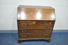 A GEORGIAN OAK BUREAU, with a fall front door enclosing a fitted interior above two short drawers