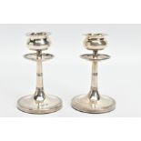 A PAIR OF SILVER EDWARDIAN DWARF CANDLESTICKS, each weighted candlestick designed with a tapered