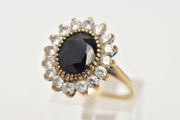 A 9CT GOLD SAPPHIRE CLUSTER RING, an oval cut sapphire claw set with a halo of circular cut cubic