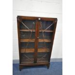 AN EARLY 20TH CENTURY OAK BOOKCASE with two glazed doors on turned feet, width 82cm x depth 27cm x