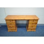 A MODERN PINE KNEE HOLE DESK/ DRESSING TABLE with two banks of four drawers, width 140cm x depth