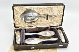 A SIX PIECE SILVER VANITY TRAVEL SET, comprising of a circular mirror, hair brush and clothes