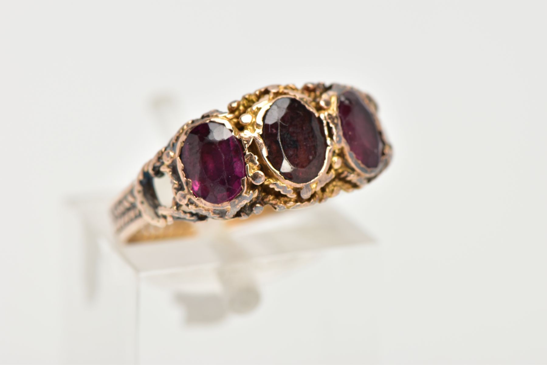 A THREE STONE GARNET RING, three oval cut garnets set within a rope twist surround leading on to the - Image 4 of 4