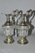 A PAIR OF DECORATIVE GLASS AND EPNS MINIATURE CLARET JUGS, the handles cast as mythical creatures,