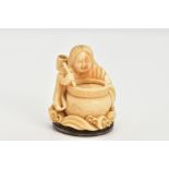 A CHINESE IVORY NETSUKE, a small carved ivory netsuke depicting a person at a cooking pot, floral