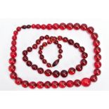 TWO RED PLASTIC BEAD NECKLACES, both comprising of a single row of graduated spherical beads, one