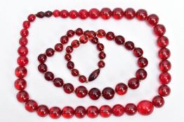 TWO RED PLASTIC BEAD NECKLACES, both comprising of a single row of graduated spherical beads, one