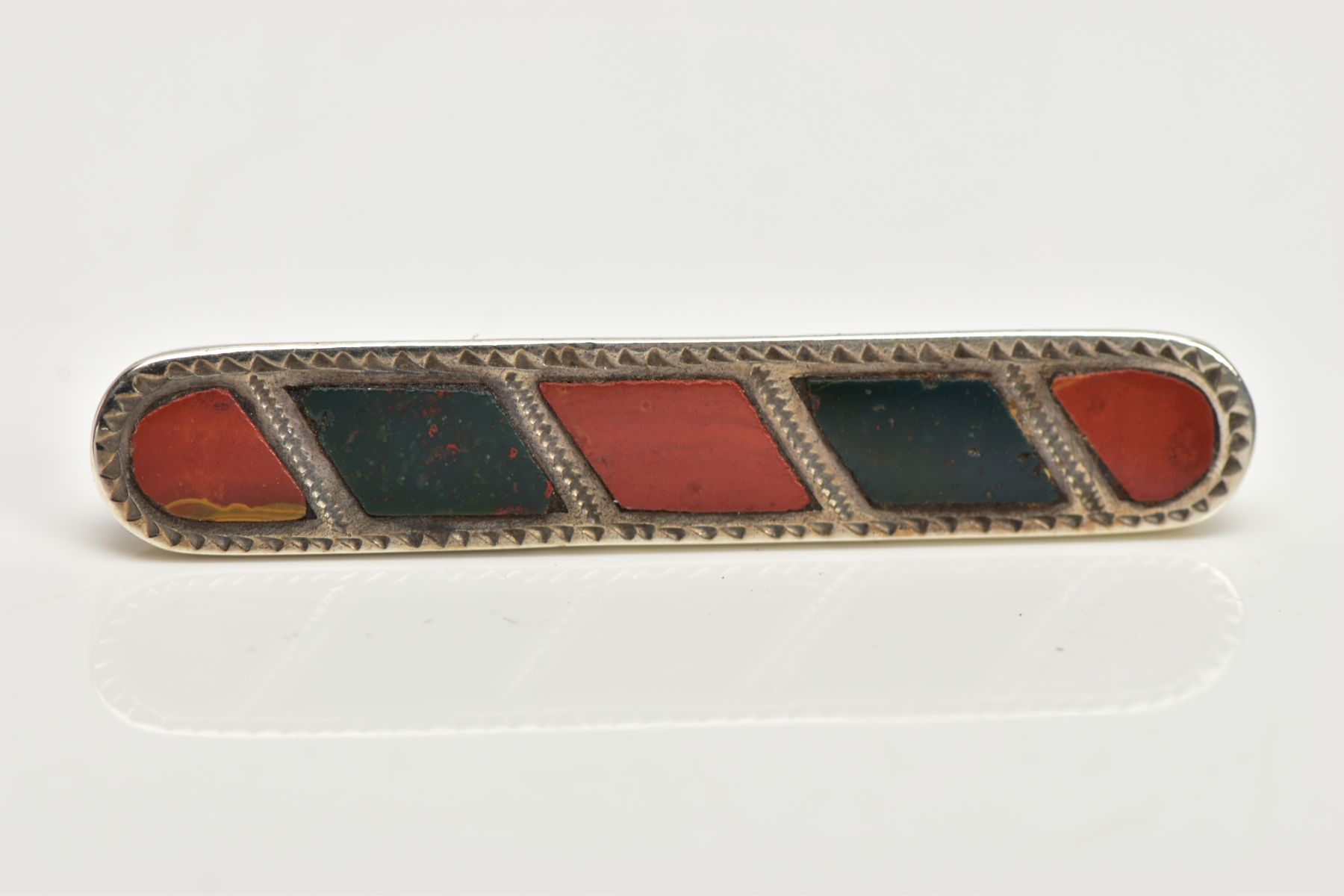 A LATE VICTORIAN SILVER HARDSTONE BROOCH, of an elongated outline inlaid with bloodstone and jasper,