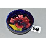 A SMALL MOORCROFT POTTERY FOOTED BOWL, with tubelined red/blue Hibiscus pattern on a dark blue