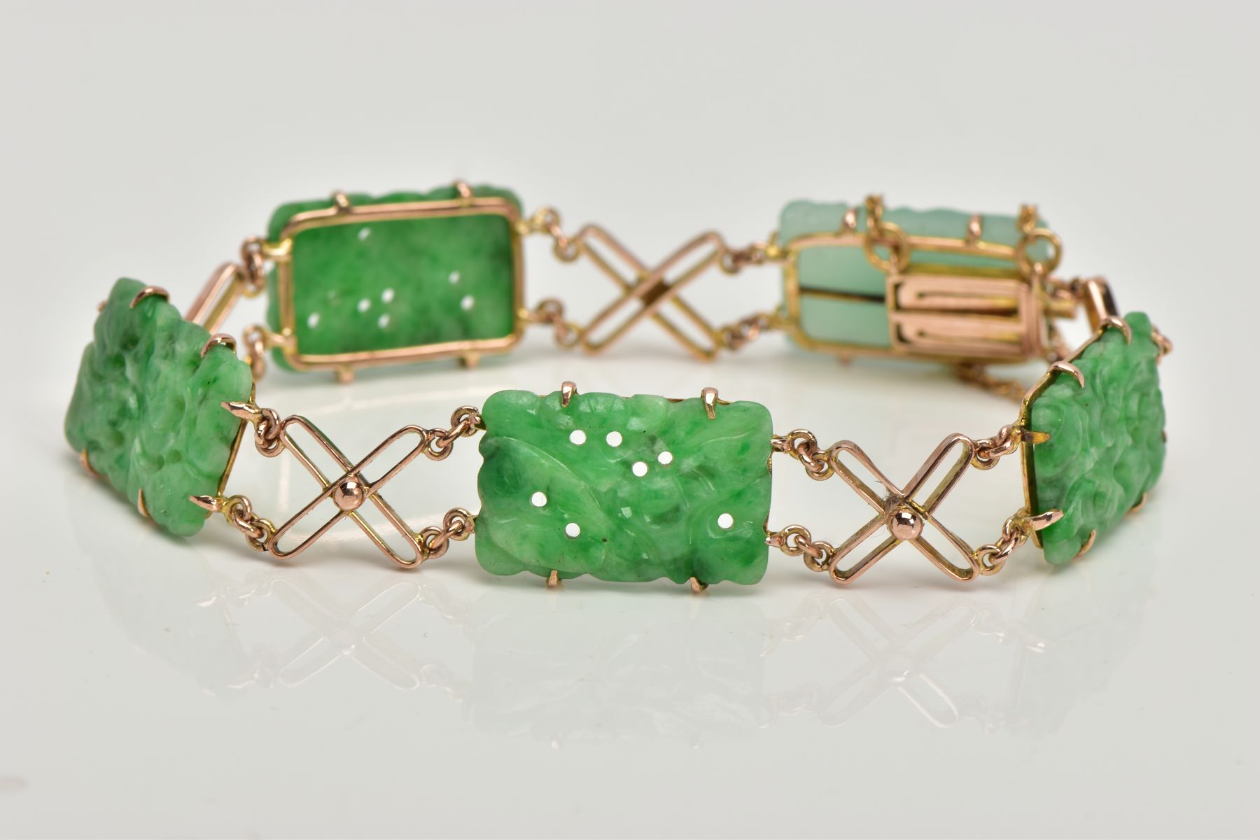A JADEITE PANEL BRACELET, designed as four rectangular carved jadeite panels and one replacement