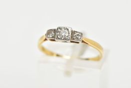 A YELLOW METAL THREE STONE DIAMOND RING, centring on a round brilliant cut diamond within a square