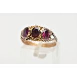 A THREE STONE GARNET RING, three oval cut garnets set within a rope twist surround leading on to the