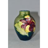 A SMALL MOORCROFT POTTERY BALUSTER VASE, decorated with tubelined Hibiscus pattern on a green/
