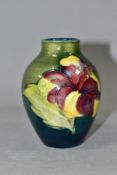 A SMALL MOORCROFT POTTERY BALUSTER VASE, decorated with tubelined Hibiscus pattern on a green/