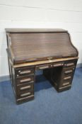 AN OAK TAMBOUR TOP PEDESTAL DESK, with nine drawers, width 122cm x depth 77cm x height 117cm (