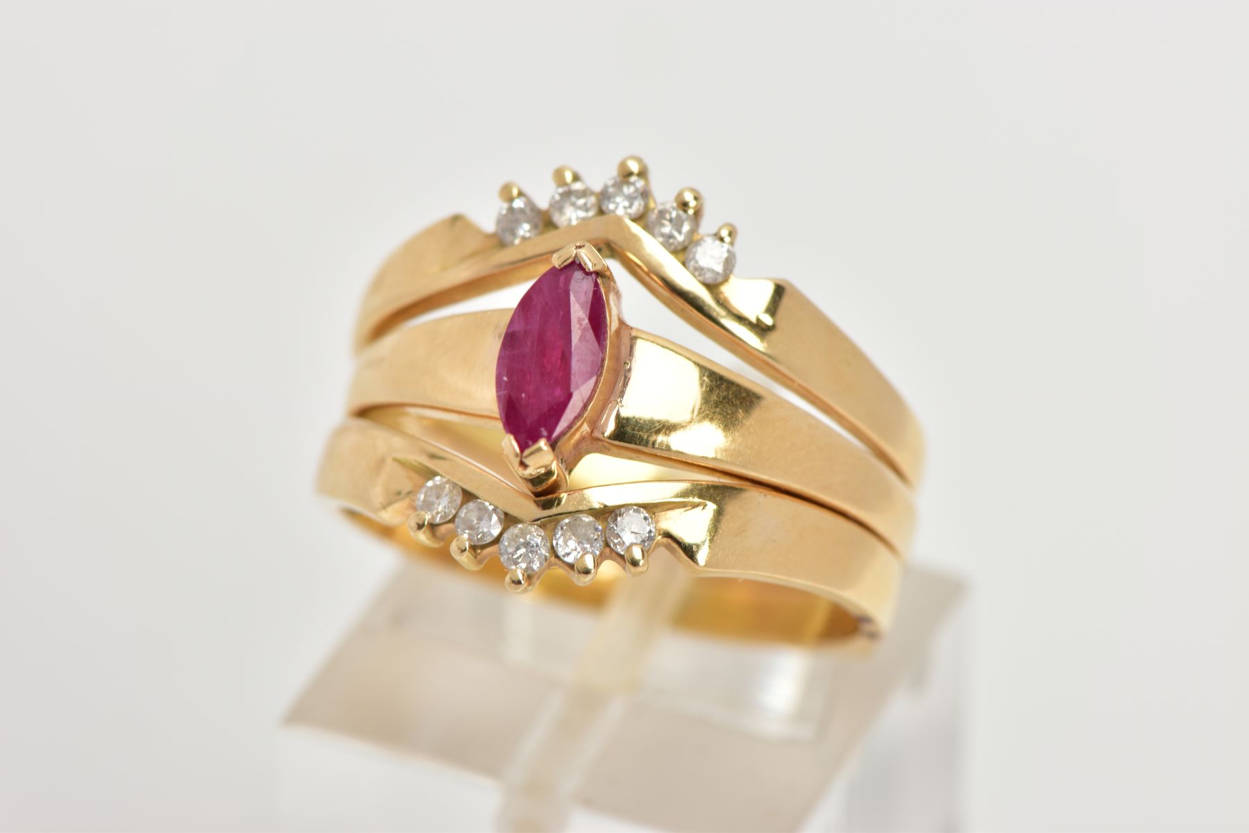 A YELLOW METAL RUBY AND DIAMOND PUZZLE RING, the centre ring designed with a tension set, marquise