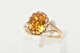 A 9CT GOLD CITRINE RING, an oval cut citrine prong set with a scallop surround and openwork gallery,